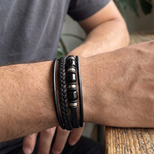 Men's black leather bracelet on wrist with braided center and metal beads