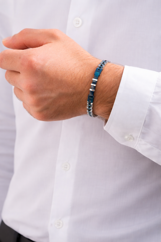 Blue and black link bracelet on wrist under a white button-up sleeve.