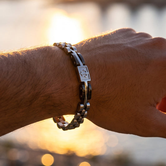 Silver and gunmetal anchor bracelet on wrist with rectangular emblem plate