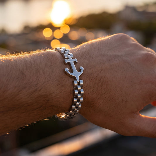 Silver anchor charm bracelet on wrist with metal link chain in warm sunlight