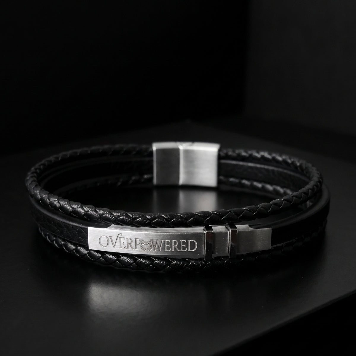 Black braided leather bracelet with engraved OVERPOWERED plate and silver buckle