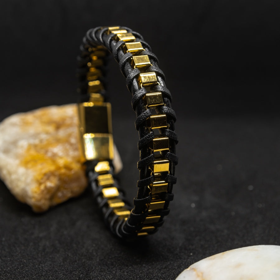 Premium braided natural leather bracelet with gold stainless steel accents, set against a dark background with stones.