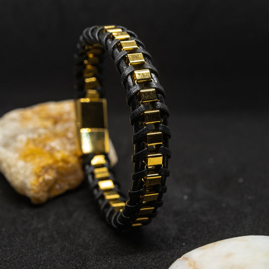 Premium braided natural leather bracelet with gold stainless steel accents, set against a dark background with stones.
