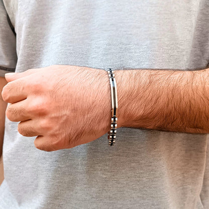 Two-tone silver and black stainless steel B-84 bracelet worn on a man's wrist, showcasing a sleek design.