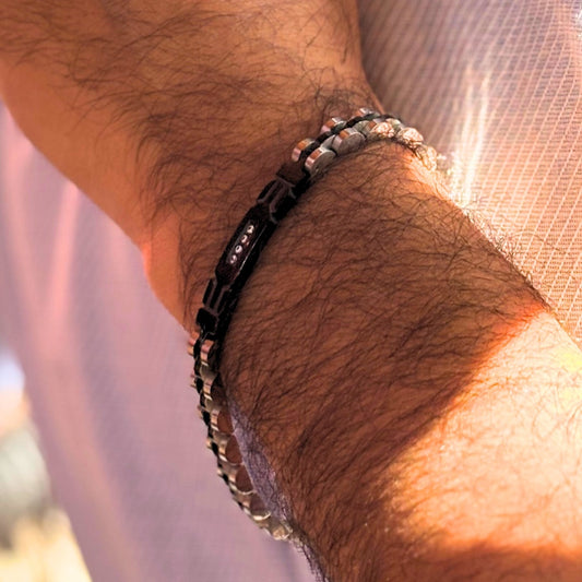 Two-tone silver and black stainless steel bracelet with zircon accents, worn on a man's wrist. Stylish and modern design.