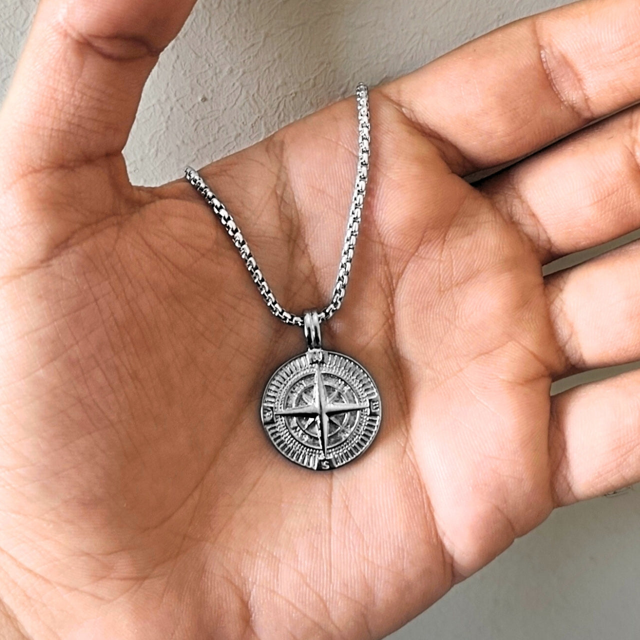 Silver steel compass pendant necklace PN-001 held in a hand, featuring intricate detailing and a sturdy chain.