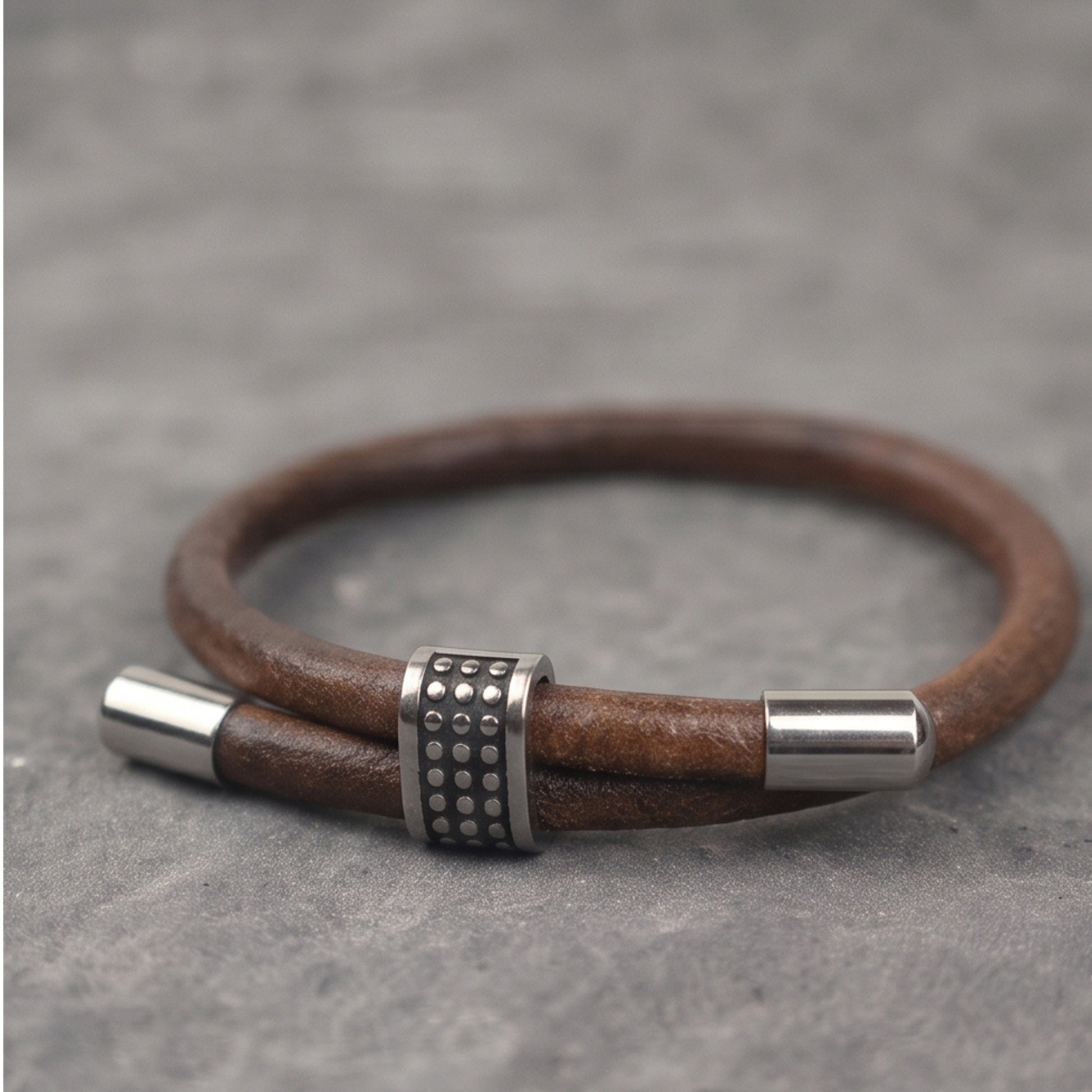 Men's brown leather bracelet with silver end caps and studded metal center