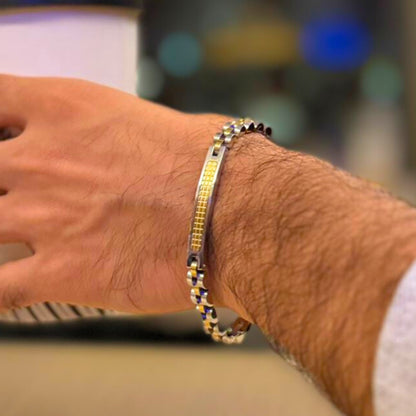 Two-tone silver and gold stainless steel B-75 bracelet on a man's wrist, featuring a sleek design and textured centerpiece.