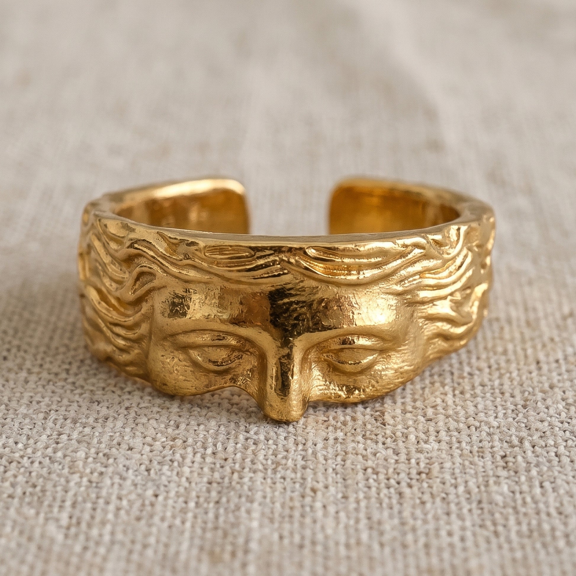 Gold sculpted face statement ring with engraved eyes and flowing hair detail