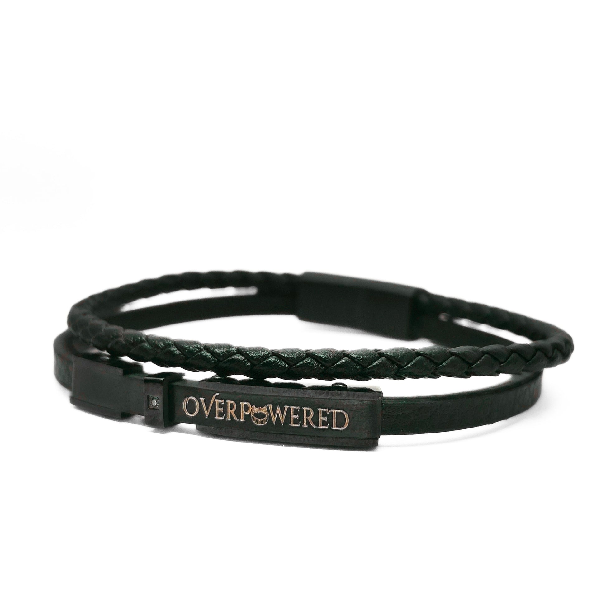 A black double-strand bracelet featuring a braided top layer and a smooth bottom layer with a rectangular metal plate engraved with the word 'OVERPOWERED' in gold.