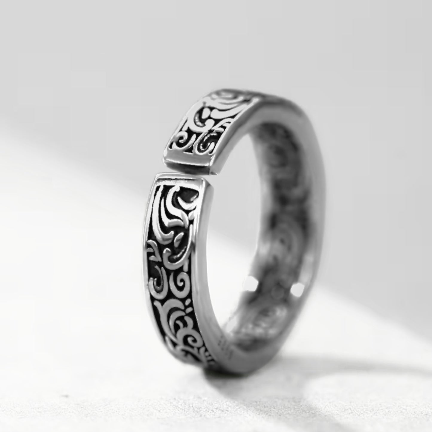 Silver tone ring with ornate black swirling pattern on the top edge