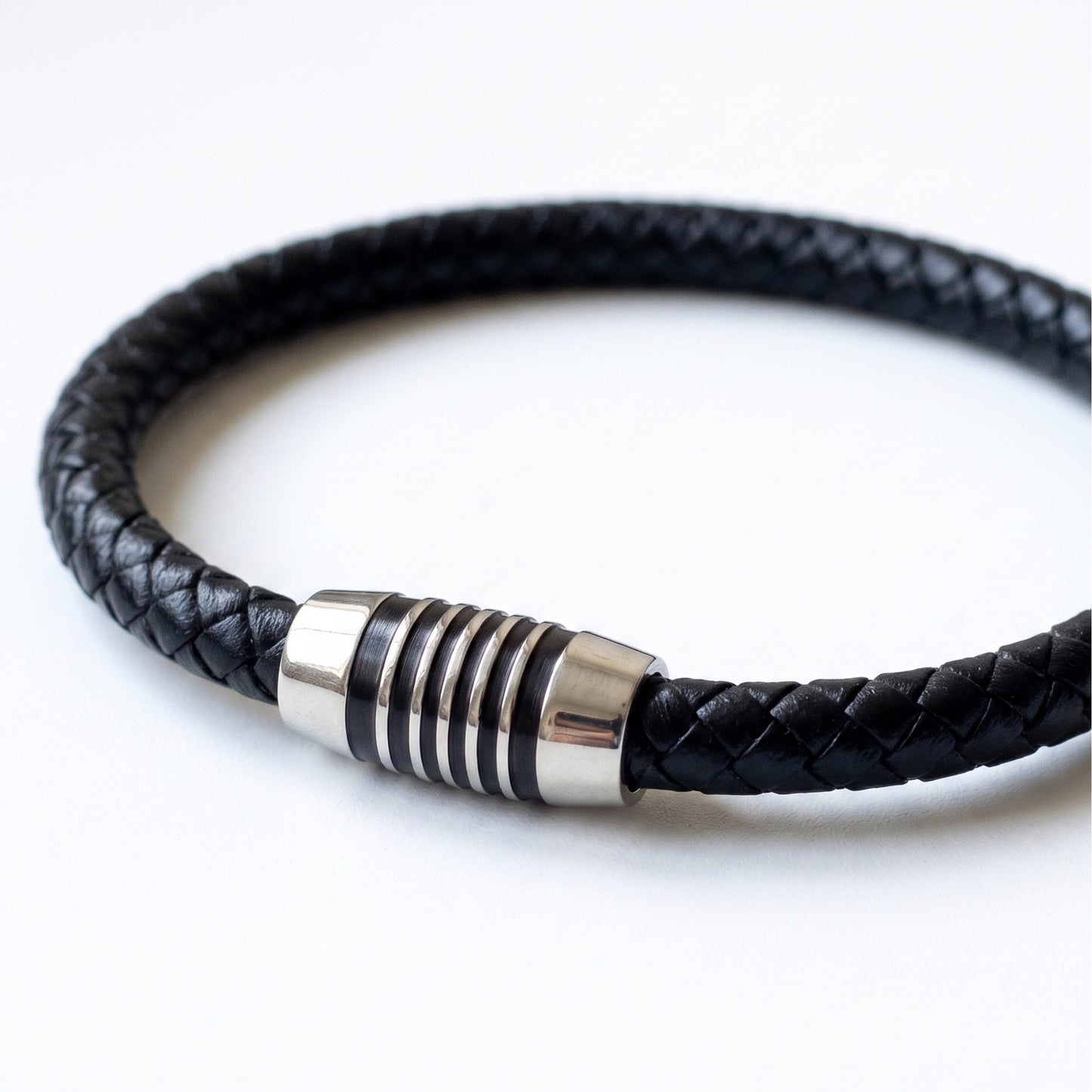 Black braided leather bracelet detail: silver-tone cylindrical clasp with rings