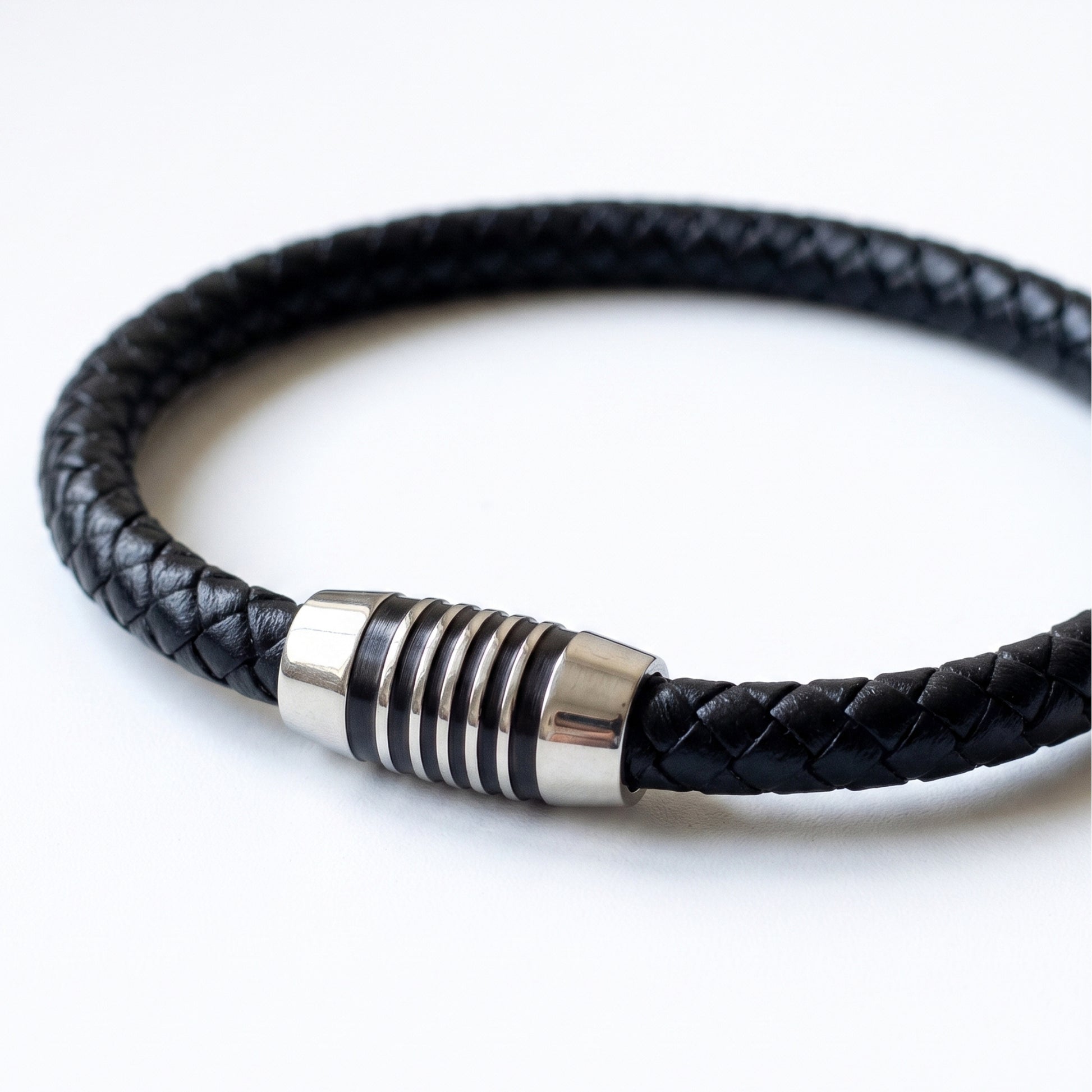 Black braided leather bracelet detail: silver-tone cylindrical clasp with rings