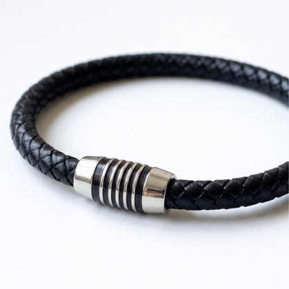 Black braided leather bracelet detail: silver-tone cylindrical clasp with rings