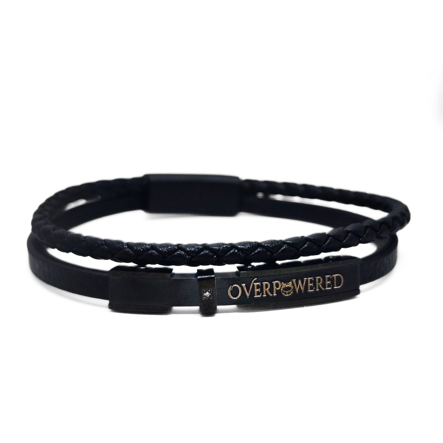 A black double-strand bracelet featuring a braided top band and a smooth bottom band with a rectangular metal clasp engraved with the word 'OVERPOWERED' in gold lettering.
