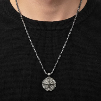 Silver steel compass pendant necklace worn on a black sweater, featuring intricate design details.