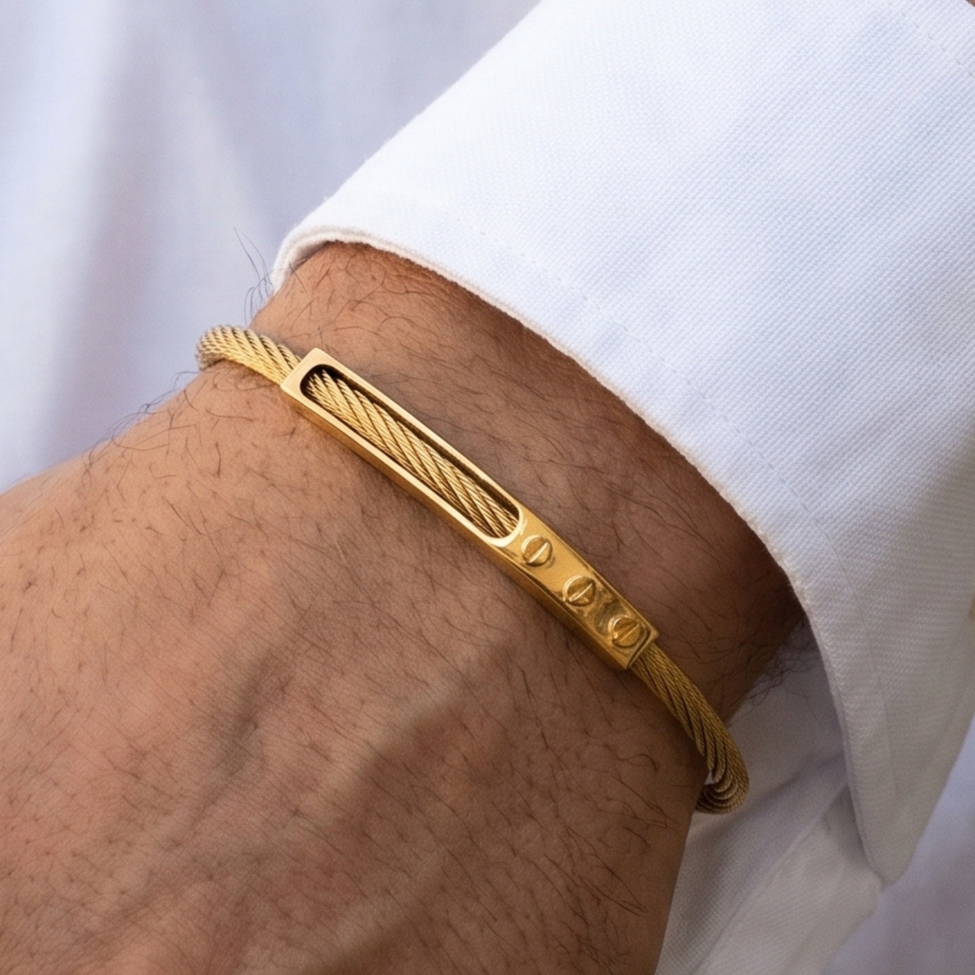 Gold bracelet on a wrist with a white shirt background