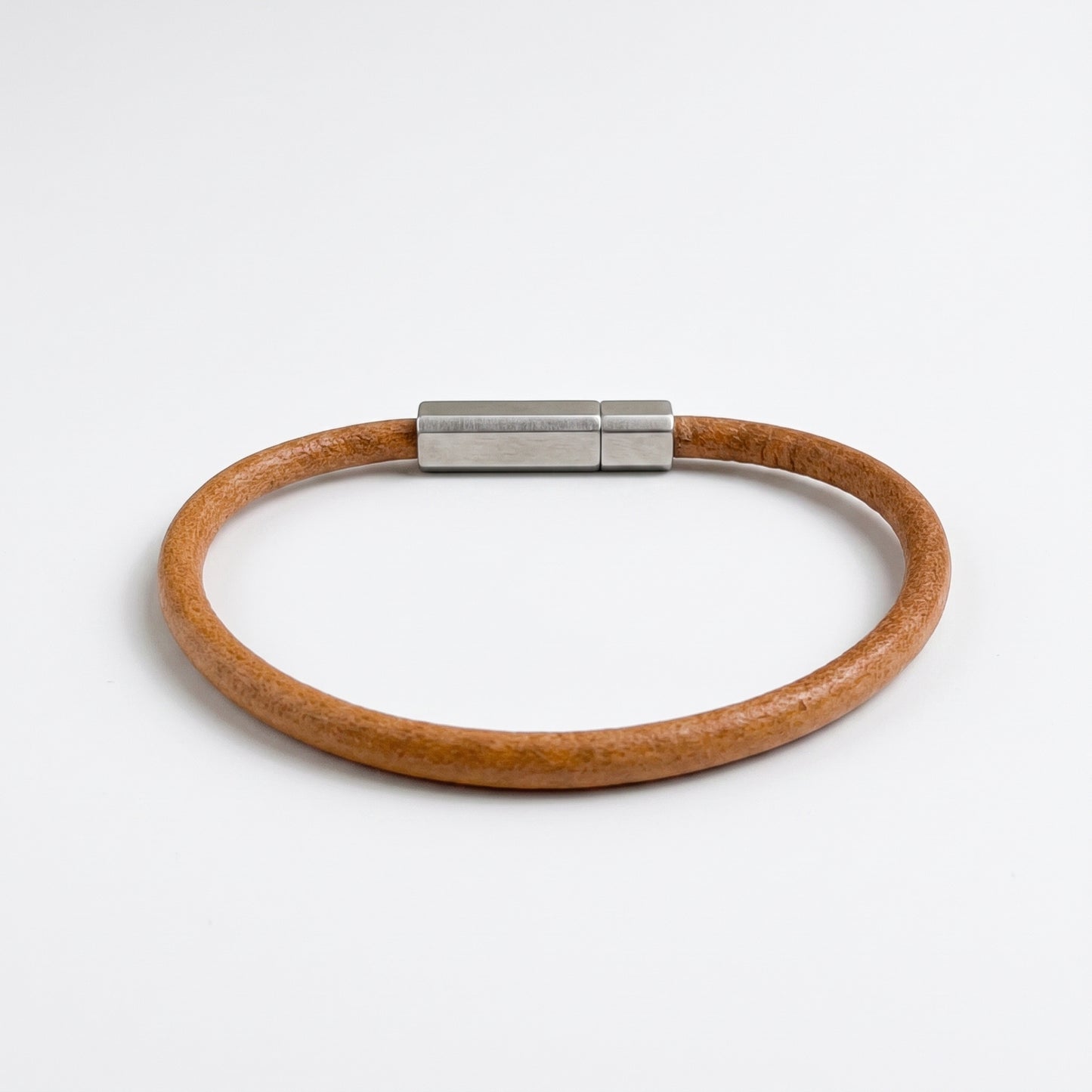 Beige-brown leather bracelet with silver magnetic bar clasp, flat on white
