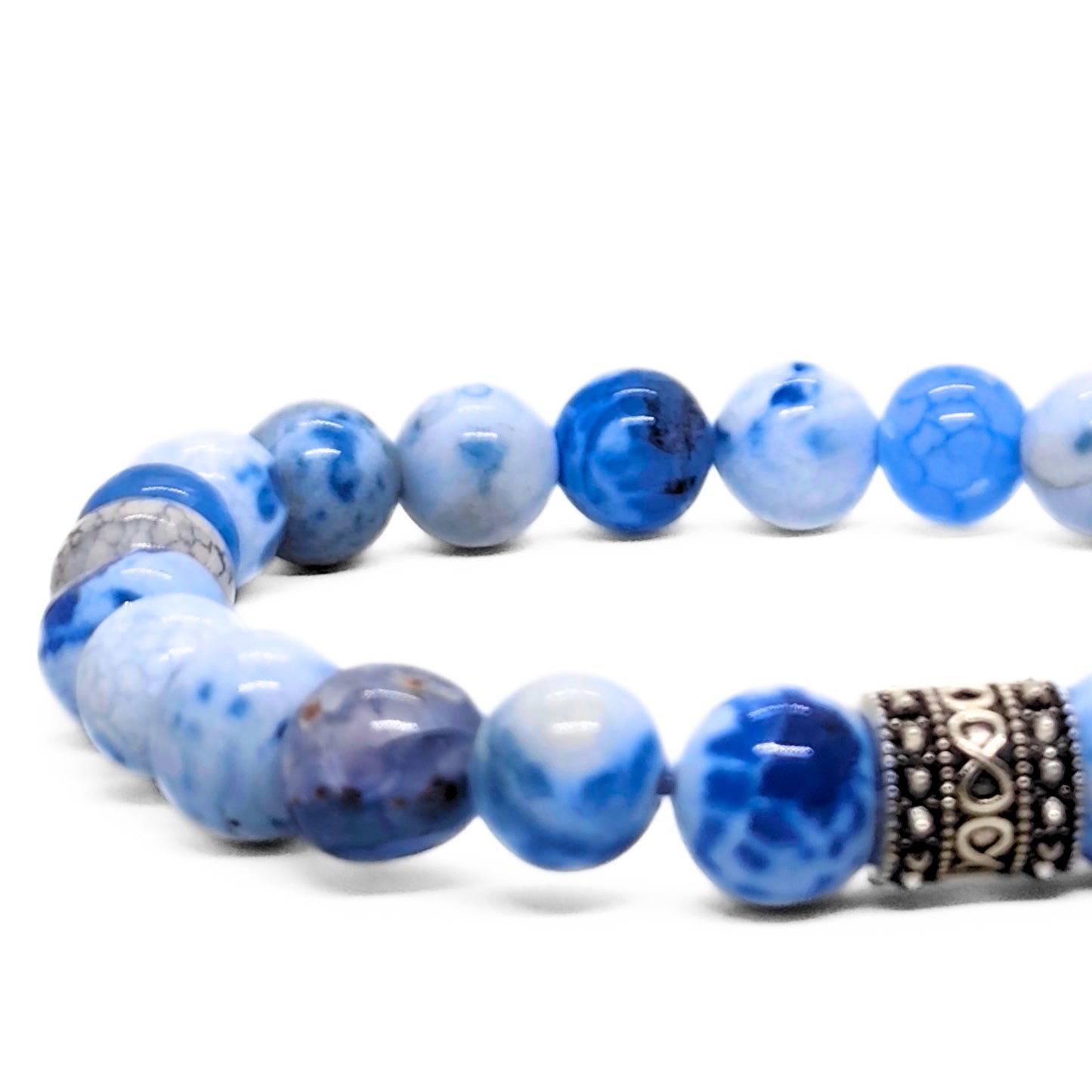 Close view of blue agate bead bracelet with dark blue beads and a black patterned spacer.