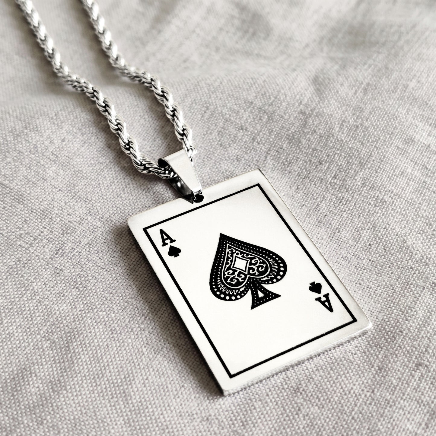 Ace of Spades card pendant with twisted silver chain, close-up angle