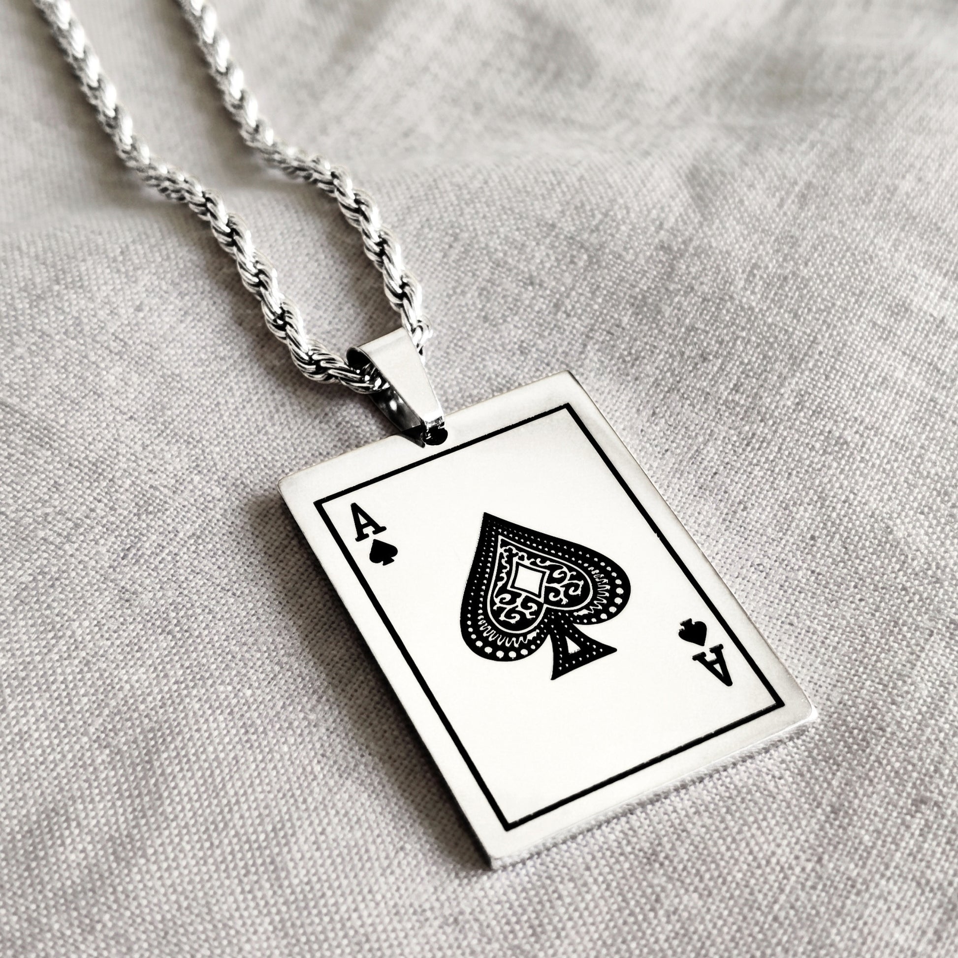 Ace of Spades card pendant with twisted silver chain, close-up angle
