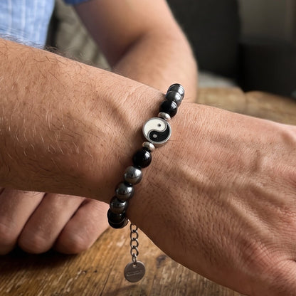 Bracelet on wrist: black and silver beads with round yin-yang charm and hanging tag