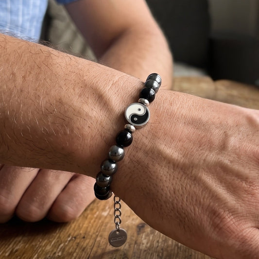 Bracelet on wrist: black and silver beads with round yin-yang charm and hanging tag