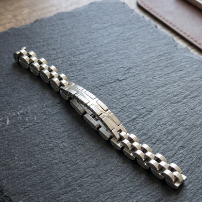 Silver and dark-toned stainless steel bracelet with X center motif on dark fabric