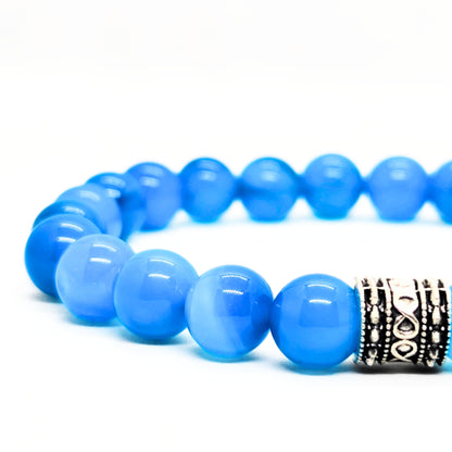 Close-up of blue agate bead bracelet with dark metal engraved centerpiece.