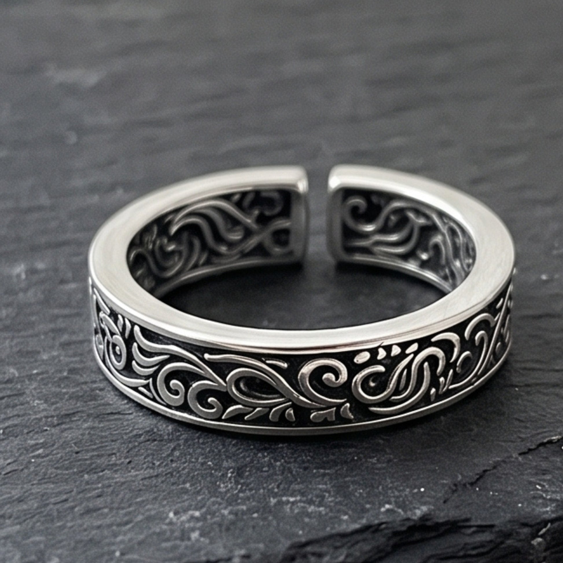 Silver tone ring featuring black filigree scrolls on a wide band