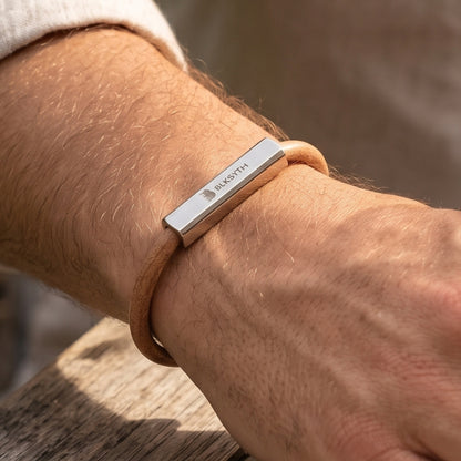 Beige-brown leather bracelet with engraved silver bar, close-up on wrist