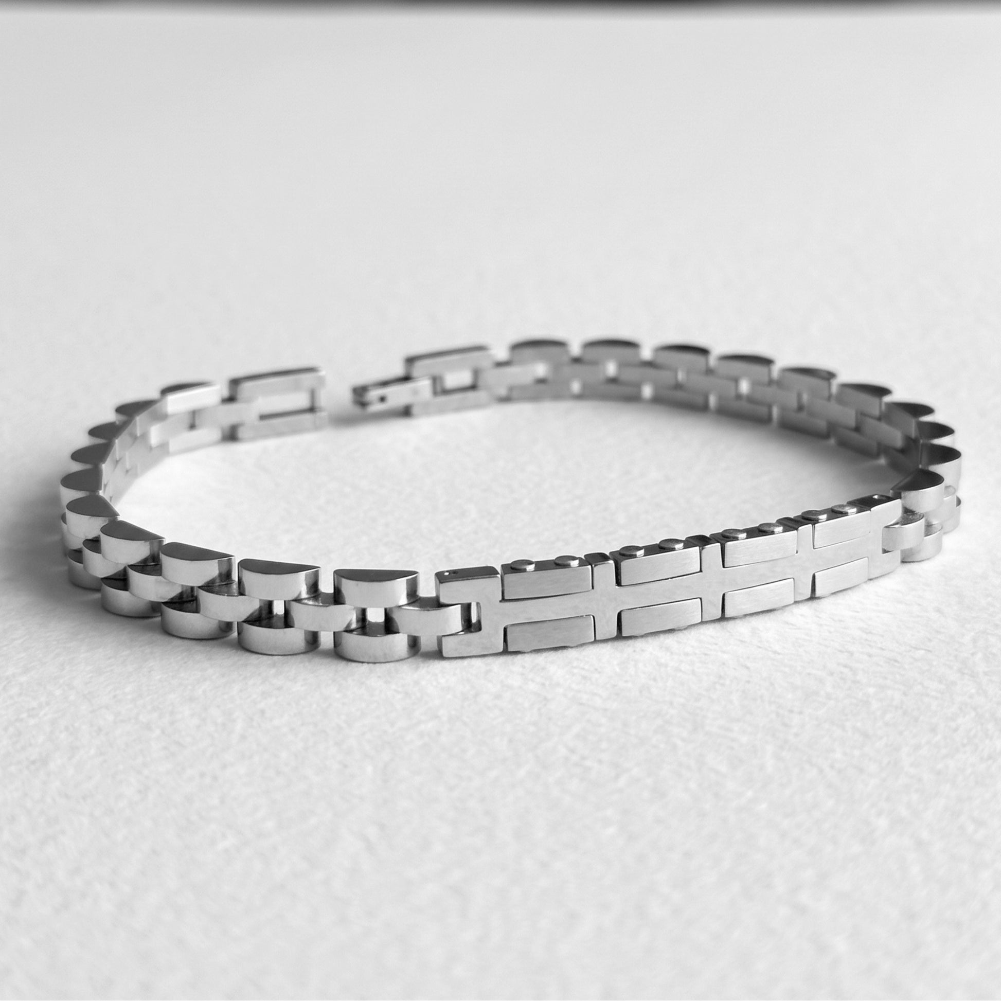 Silver stainless steel bracelet laid flat, link chain with alternating raised plates