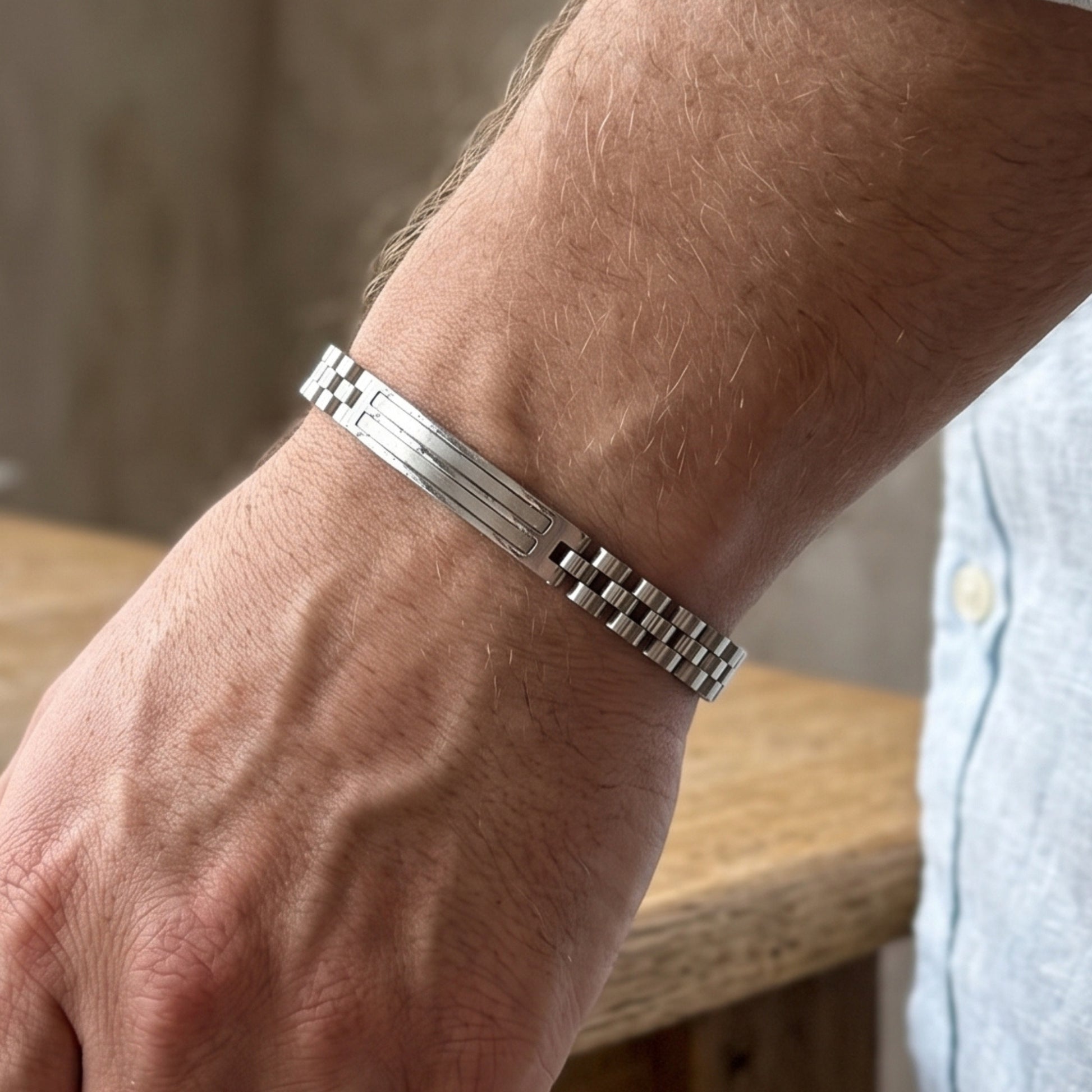 Silver stainless steel bracelet worn on arm, rectangular bar detail at center