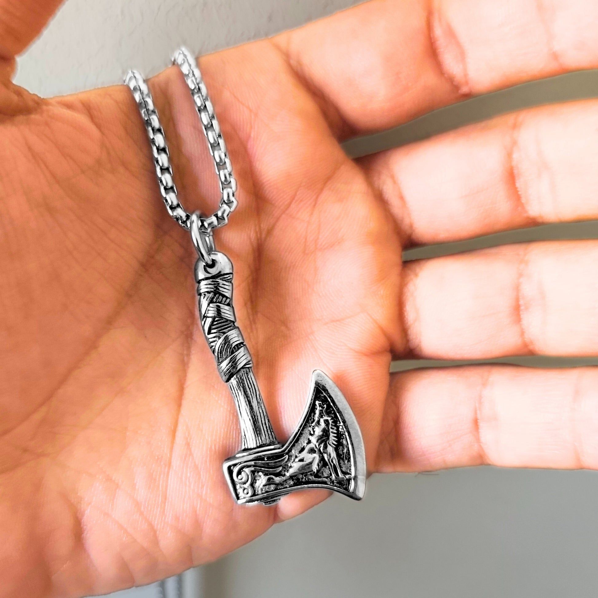 Men's Oceanic Blade Bundle B-39 pendant featuring a detailed silver axe design on a chain, held in a hand.