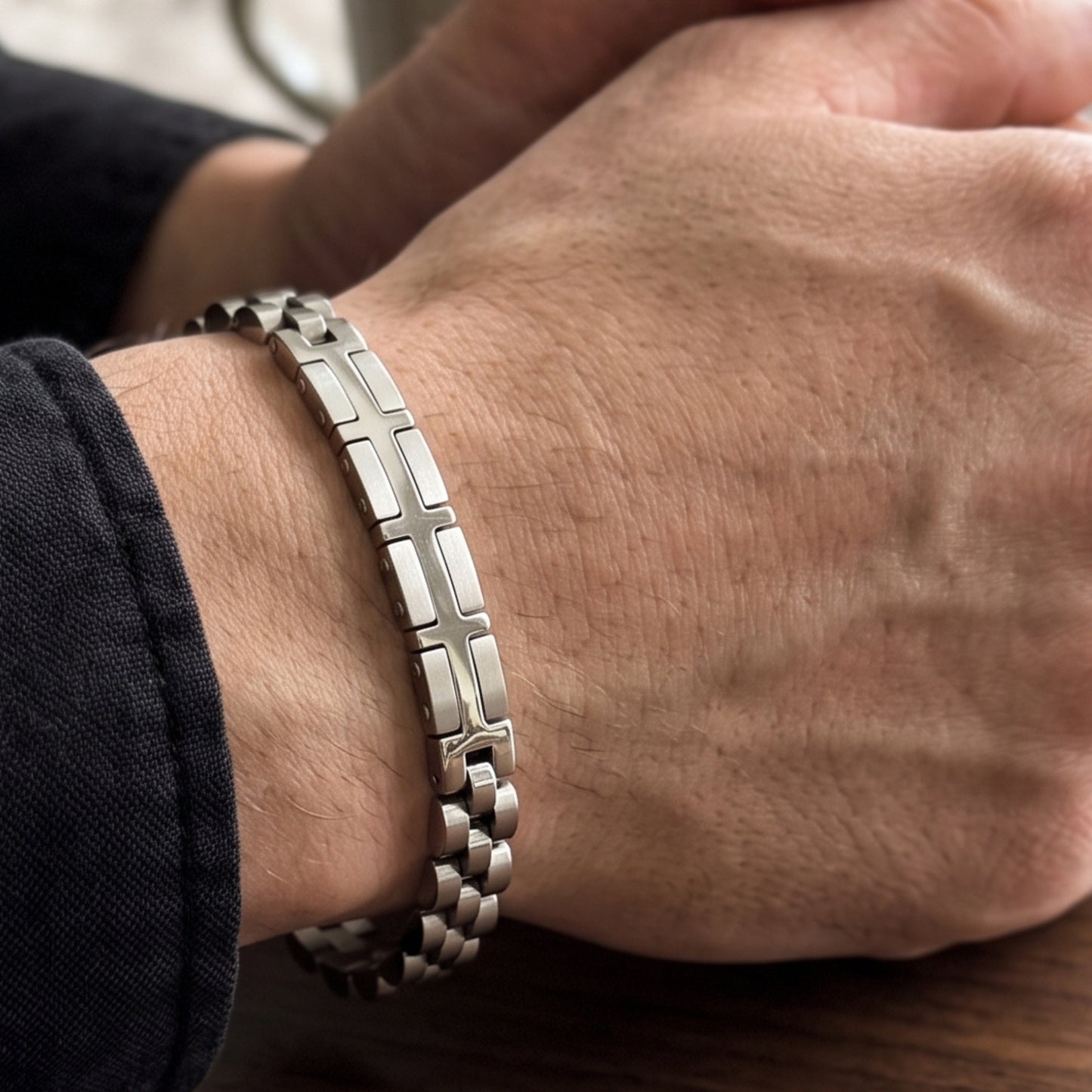 Silver stainless steel bracelet with X-shaped link panels on a man's wrist