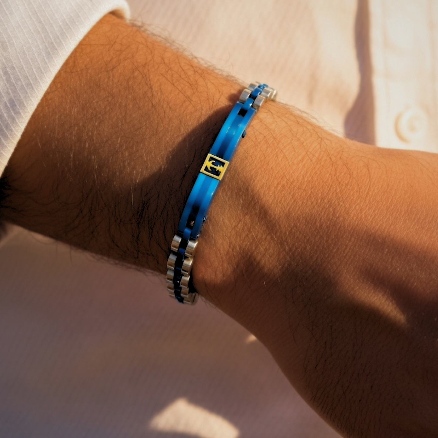 Blue and silver stainless steel B-113 men's bracelet on a wrist, featuring a yellow emblem in the center.