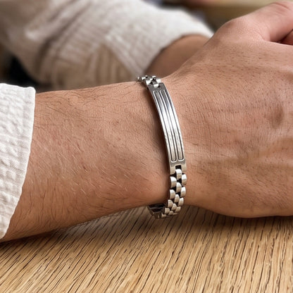Silver stainless steel bracelet on wrist, side profile showing center bar detail