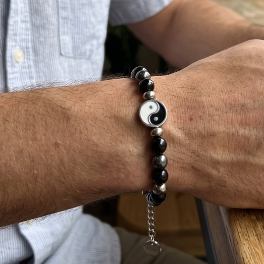 Bracelet on wrist: black and silver beads with round yin-yang charm and hanging tag