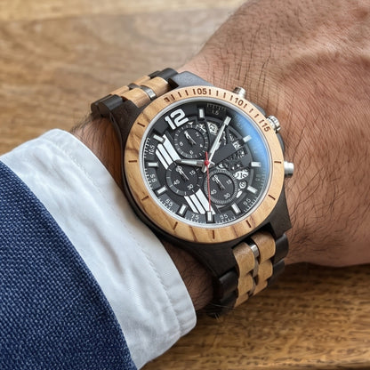 Men's wood sport watch on wrist, dark wood links with tan inserts and black chronograph dial.