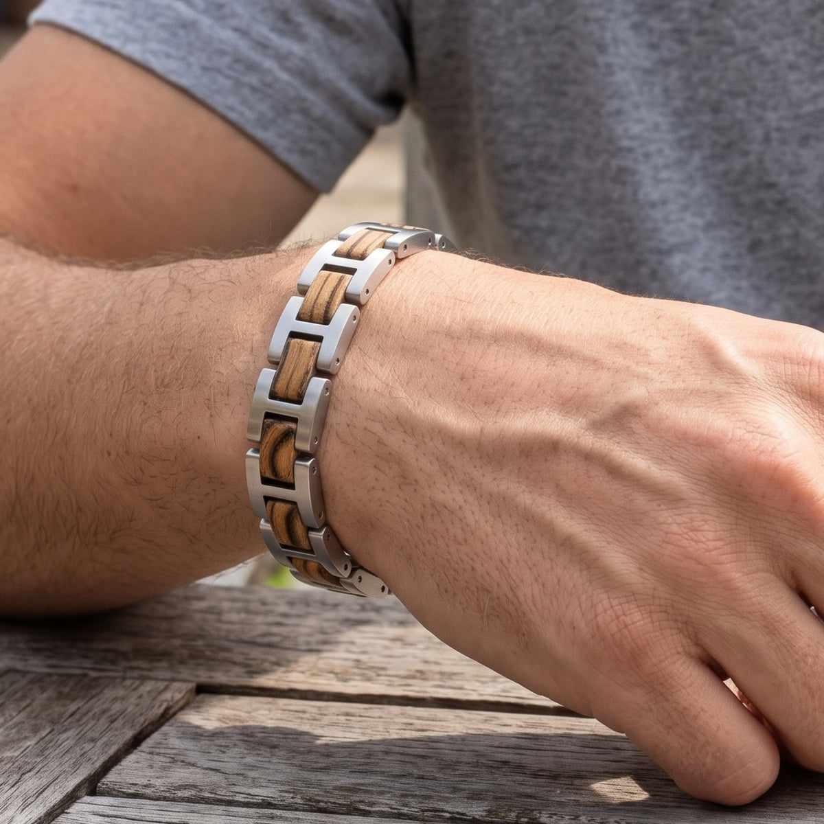 Zebrawood and stainless steel bracelet on arm resting on wood surface, Overpowered Accessories