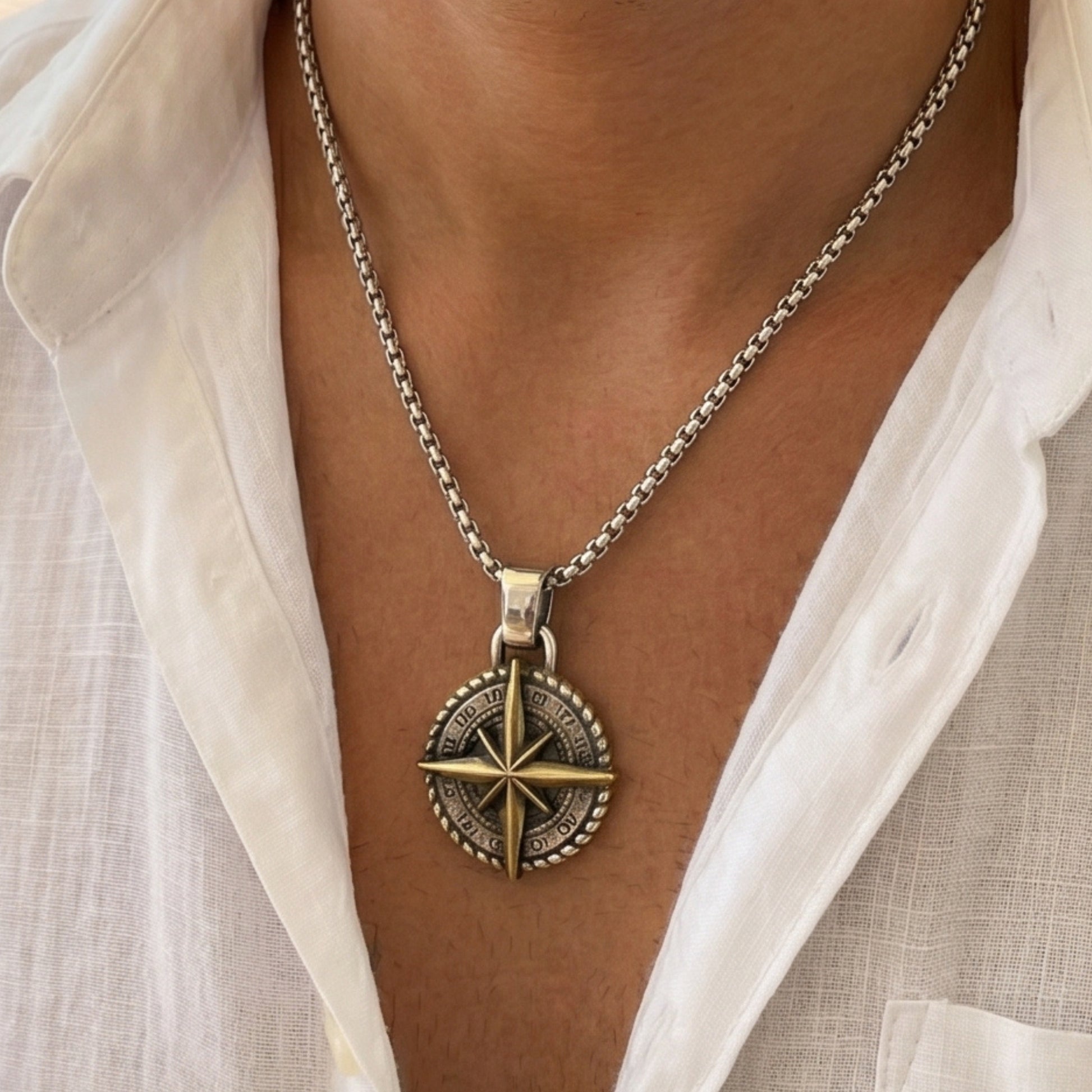 Two-tone compass pendant necklace with silver curb chain and gold star compass on dark round dial