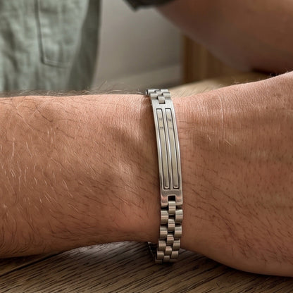 Silver stainless steel link bracelet on wrist with central engraved bar panel