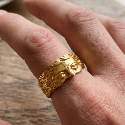 Gold sculpted face ring on hand, top view highlighting forehead and eye detailing