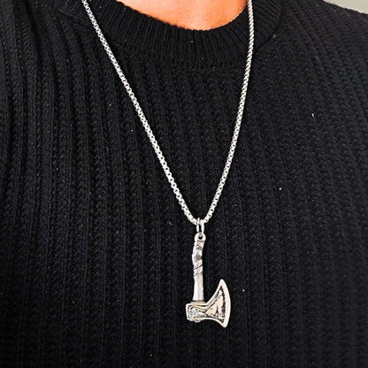Men's Oceanic Blade Bundle B-39 pendant featuring a silver axe design, worn on a chain, against a black sweater.