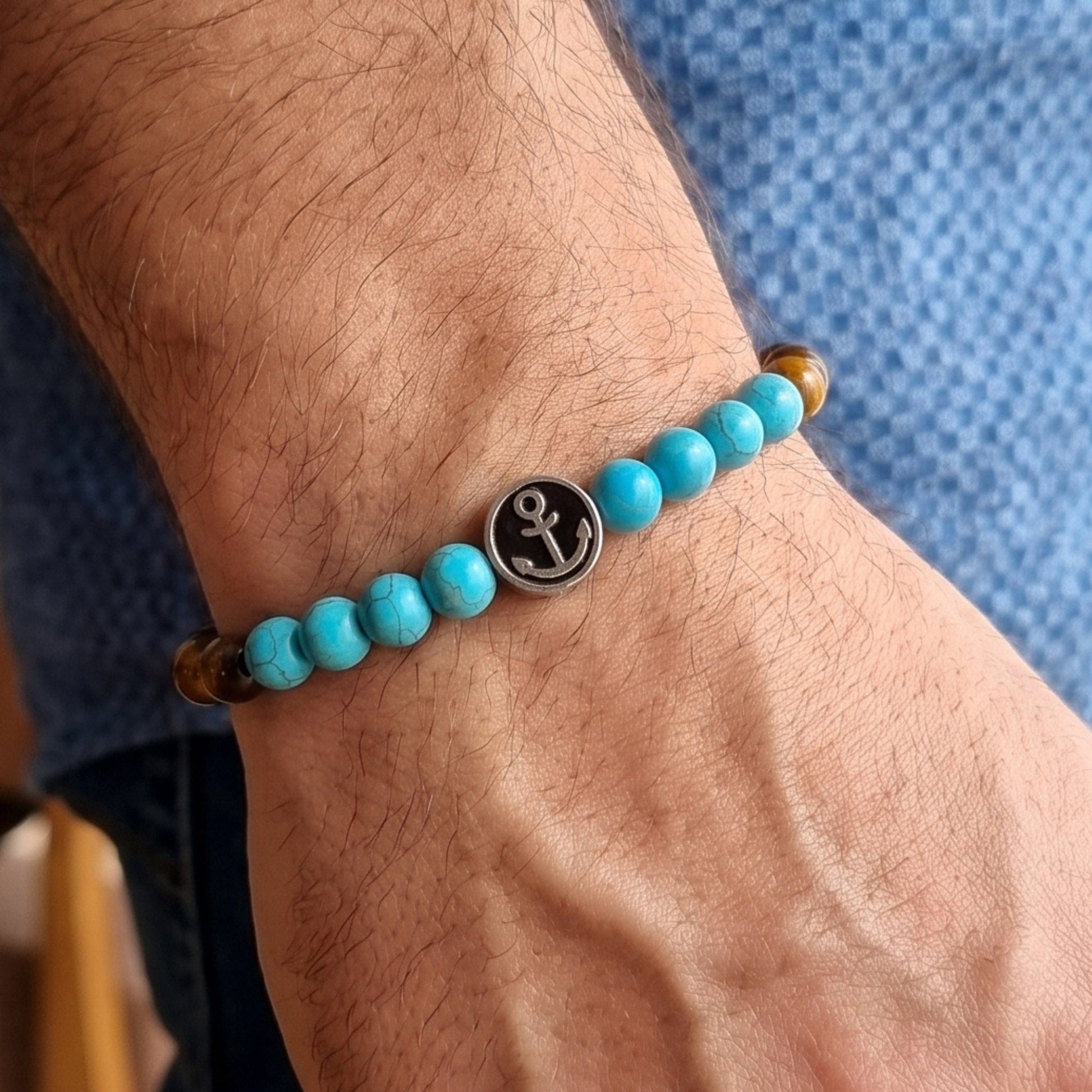 Men's turquoise and tiger eye bead anchor bracelet on wrist with silver anchor medallion