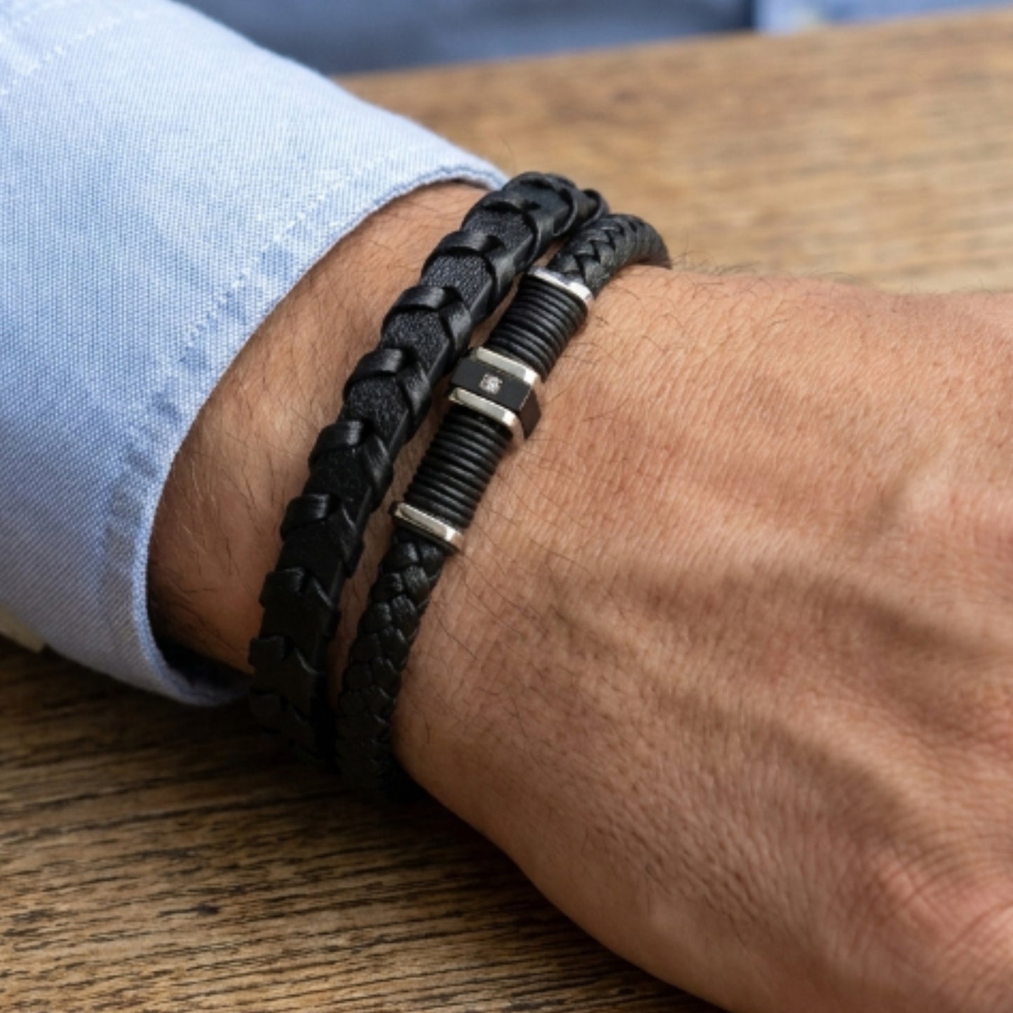 Close-up: men's black braided leather bracelet on wrist with metal clasp accents