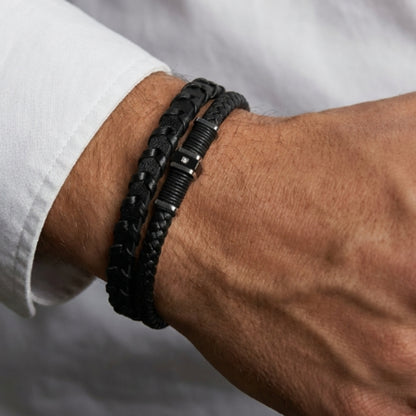Close-up: men's braided leather bracelet on wrist, black cord with dark metal links