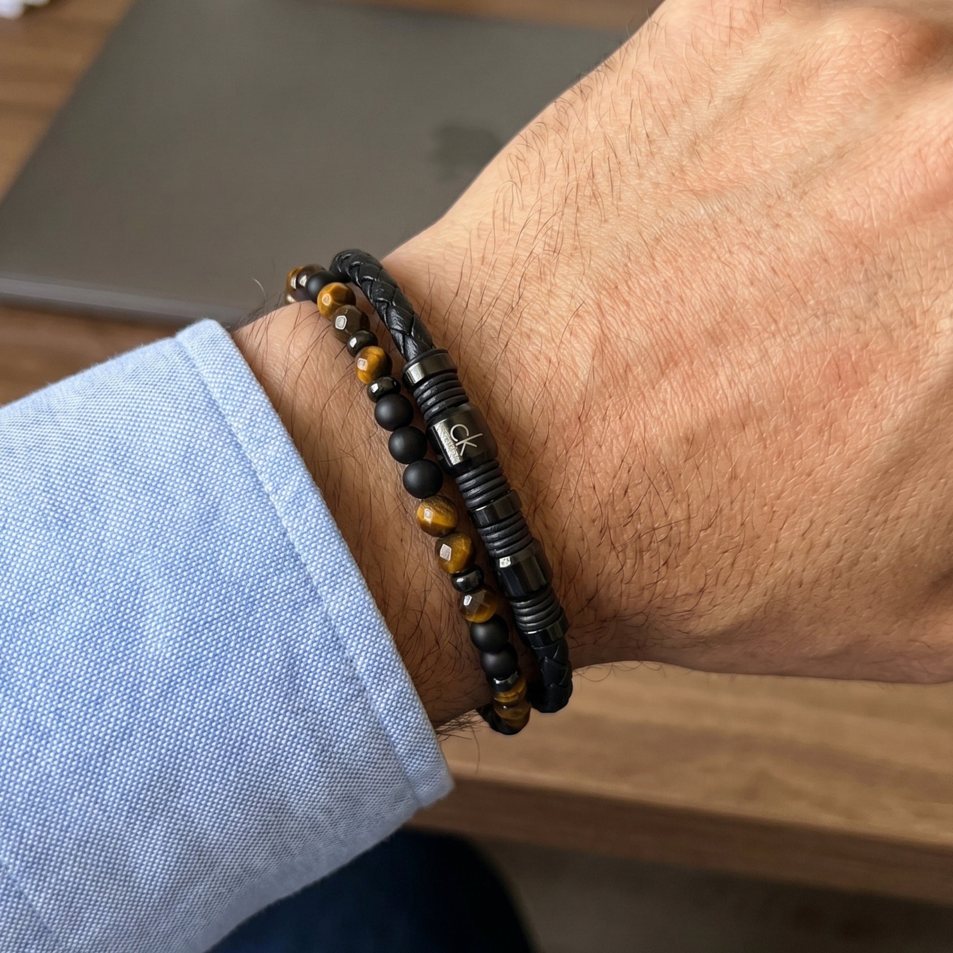 Men's wrist with braided black leather bracelet featuring tiger eye and black onyx beads