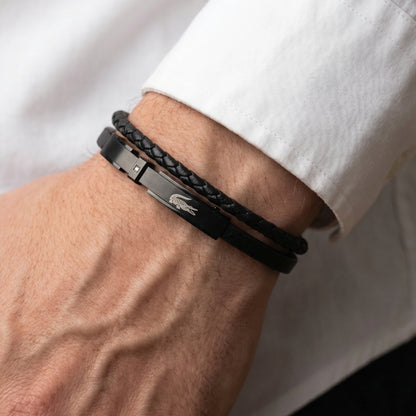 Men's black leather braided bracelet on wrist with engraved logo plate