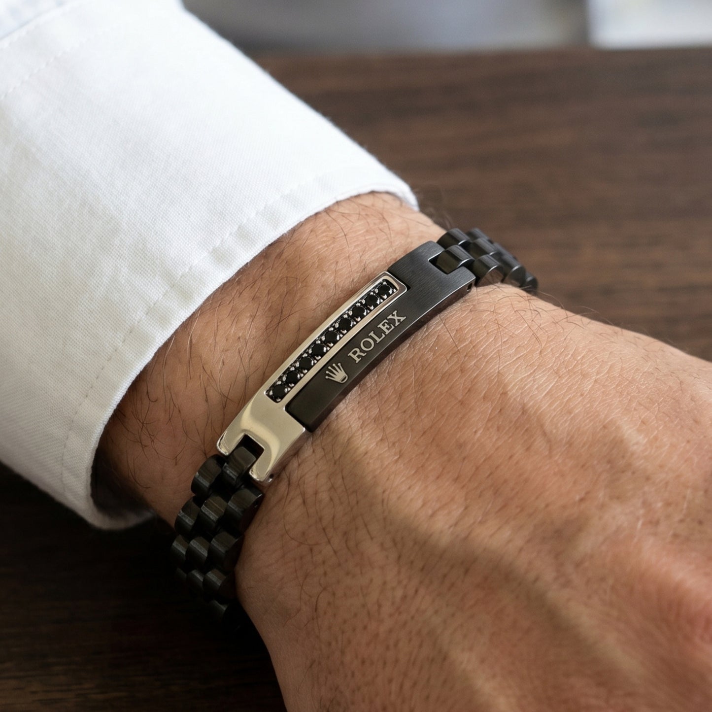 Silver and black stainless steel B-150 bracelet on a man's wrist, featuring a sleek design and clasp detail.